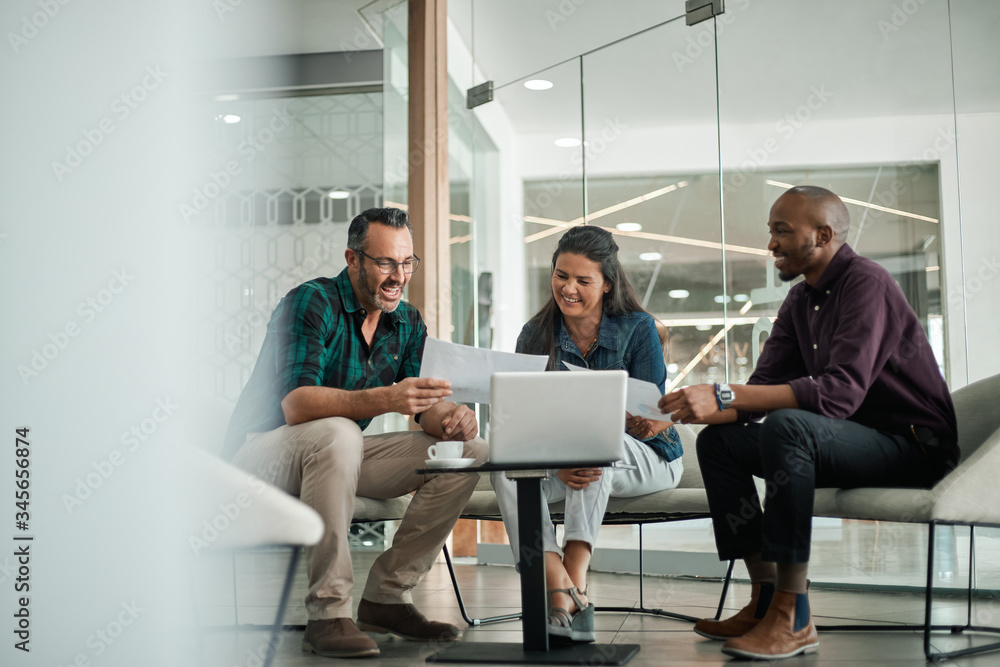 Three people in a modern office, reviewing documents 