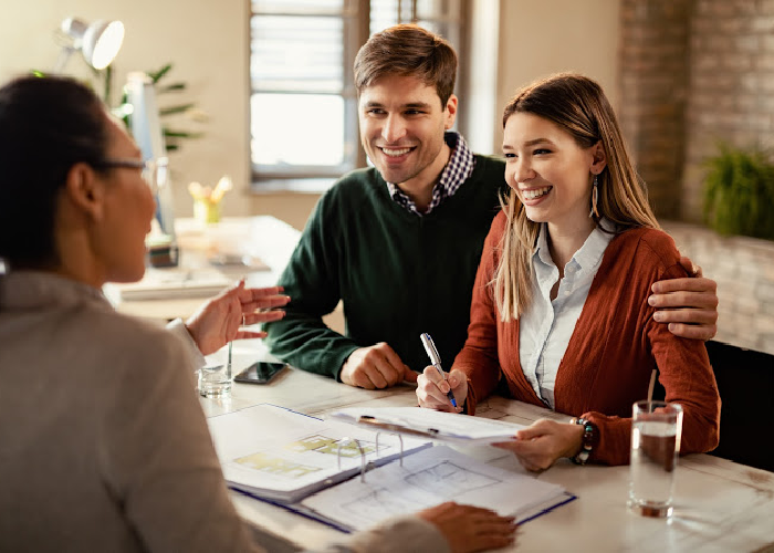 A young couple meeting with a loan officer to review and sign financial documents for a loan