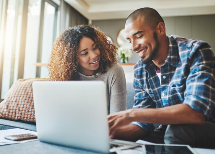 Two colleagues smiling while reviewing information together on a computer in an office setting