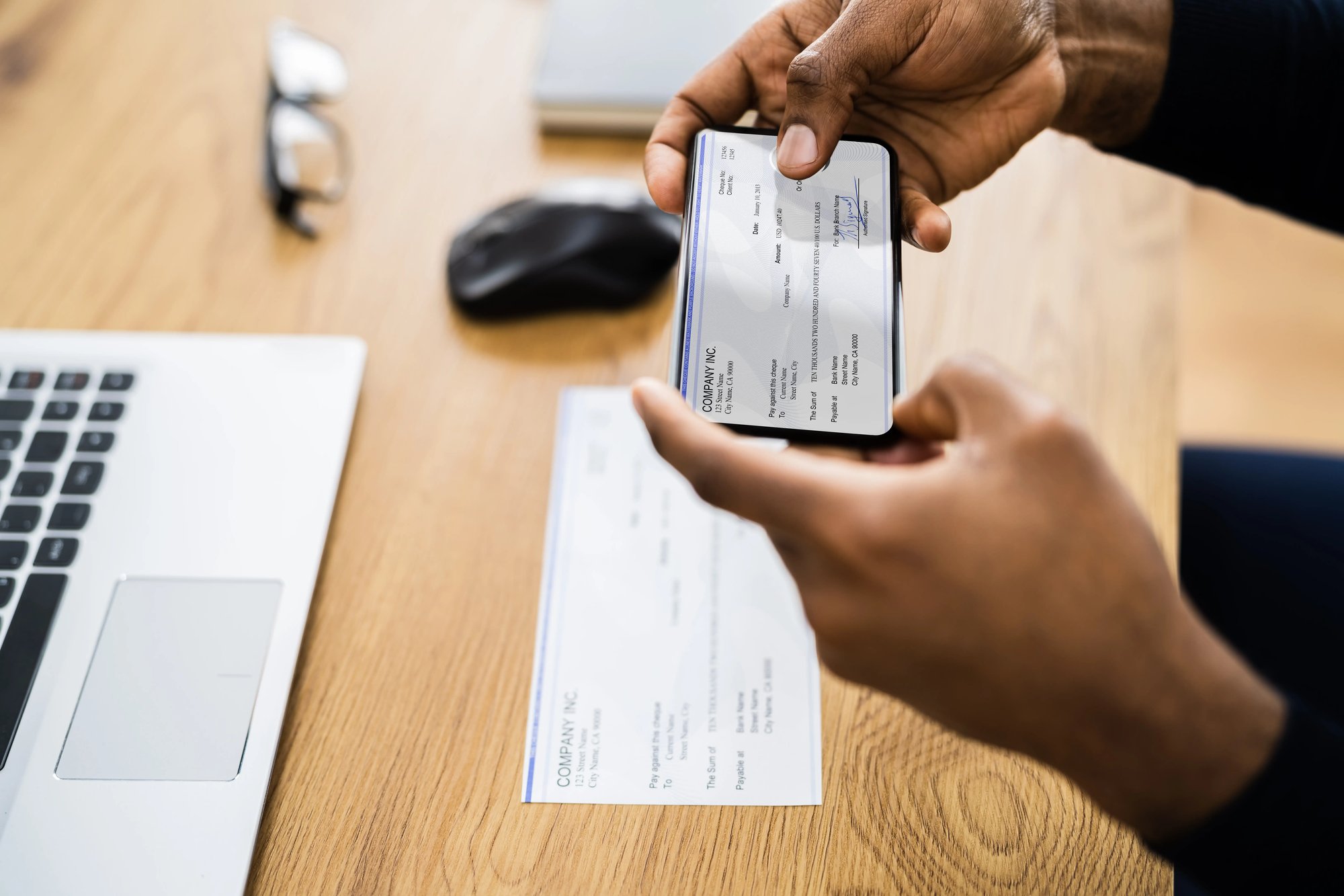 Close-up shot of a person taking a photo of a check with their smartphone in order to make a deposit