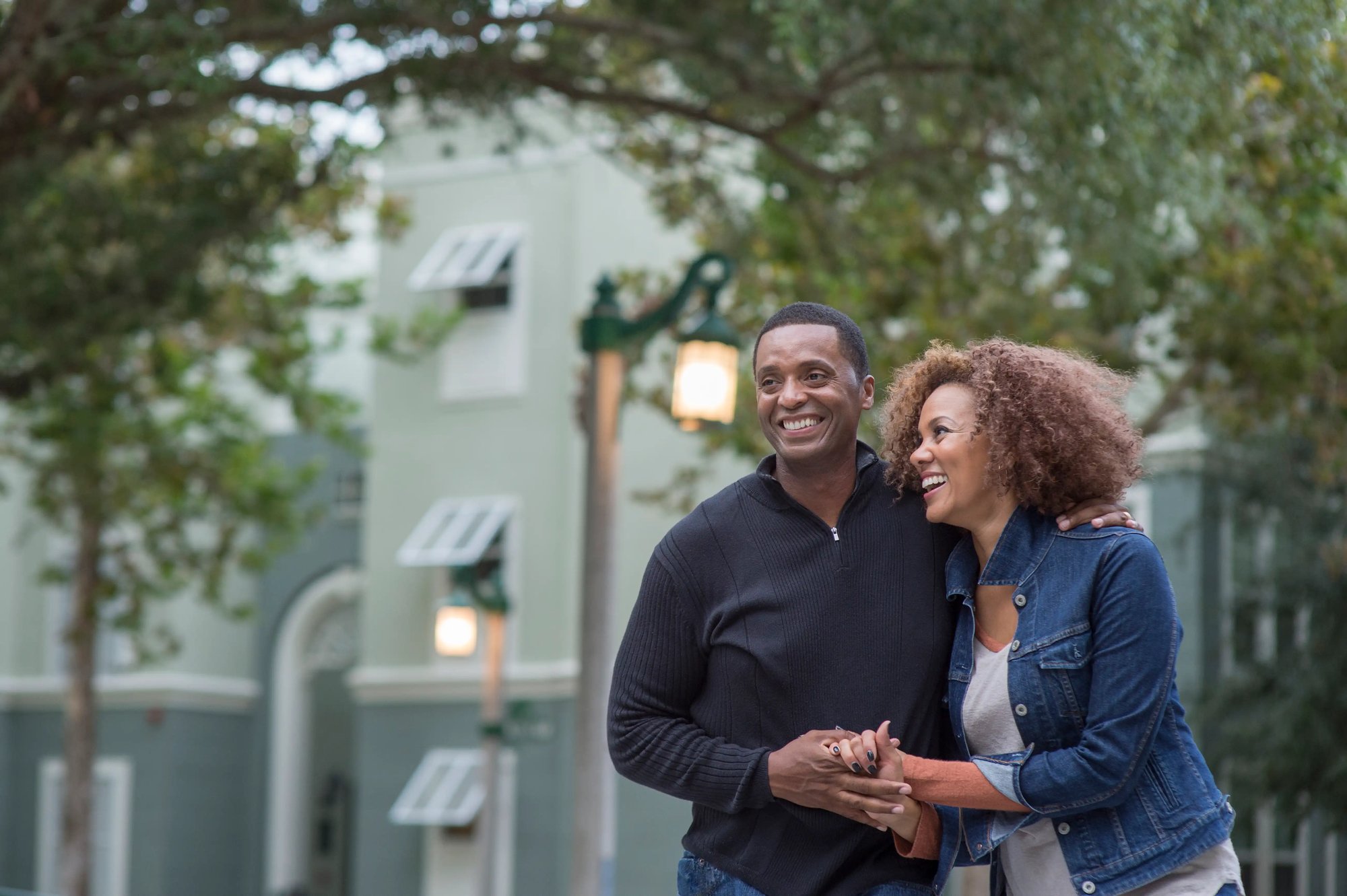 Man and woman smiling and embracing while walking together outdoors