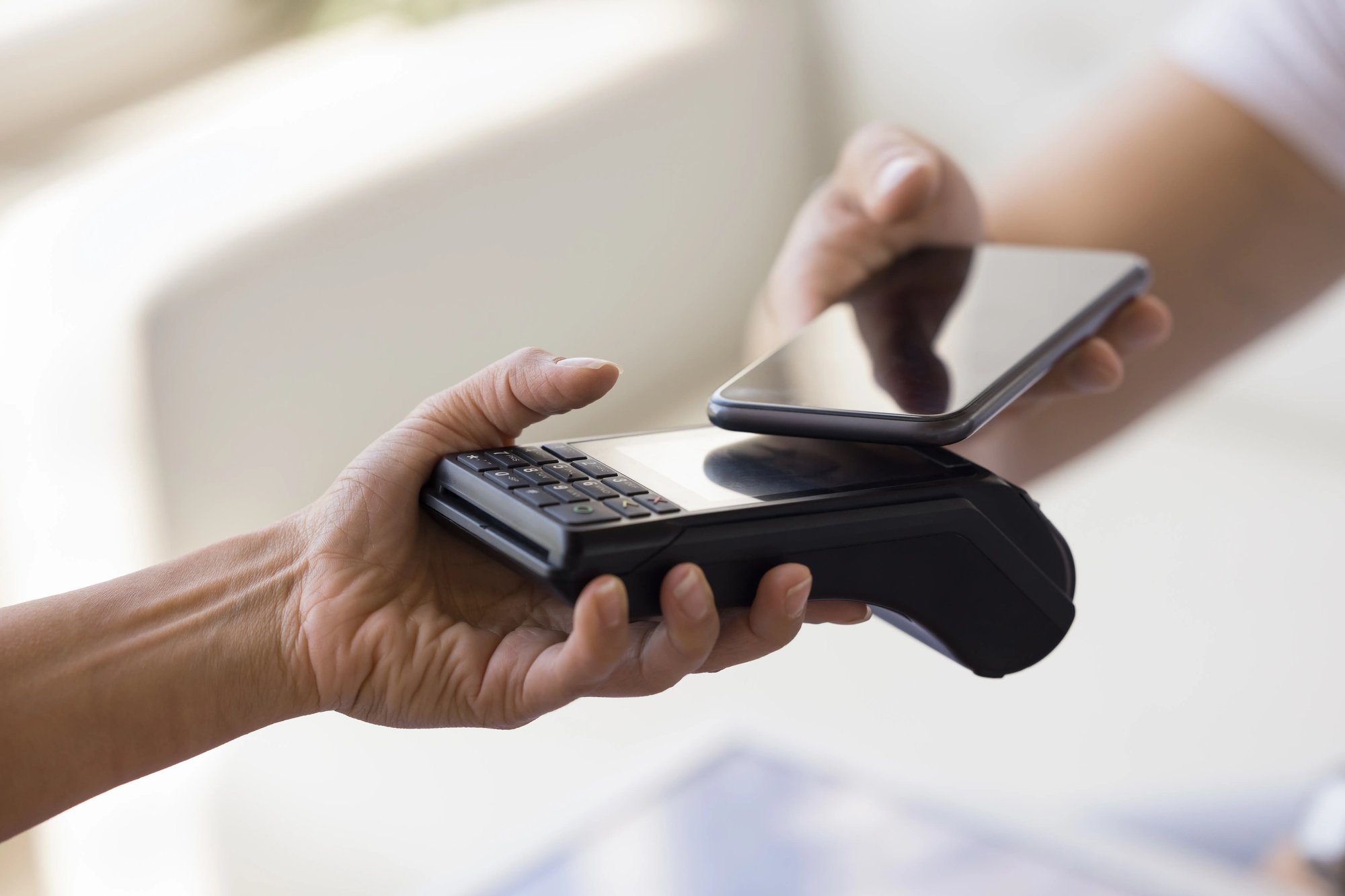Person making a contactless payment with a smartphone tapping a card reader
