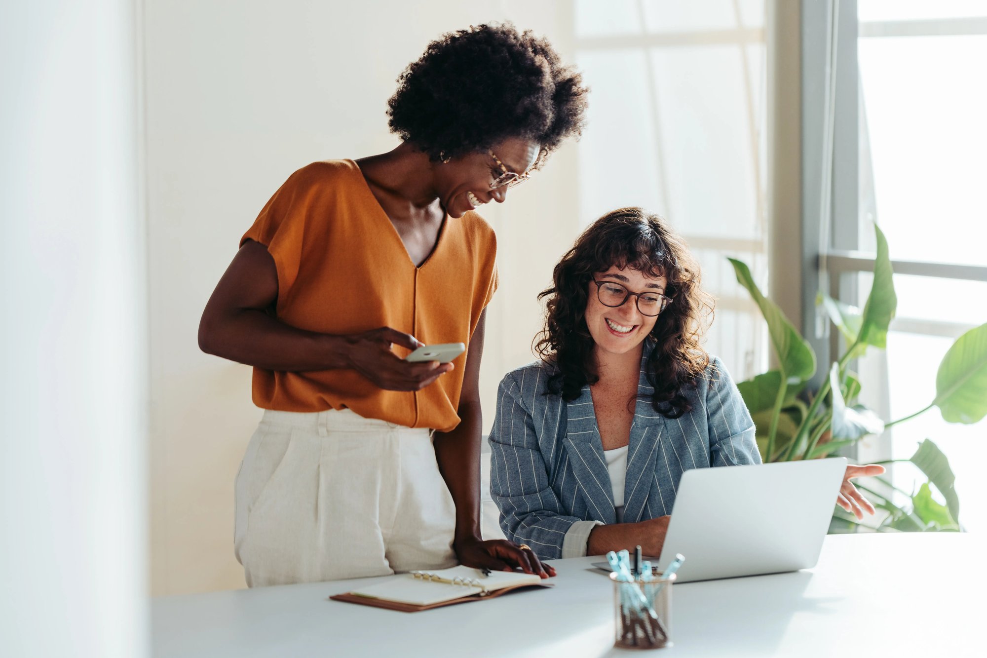 Two professional colleagues reviewing information together on a laptop in their office