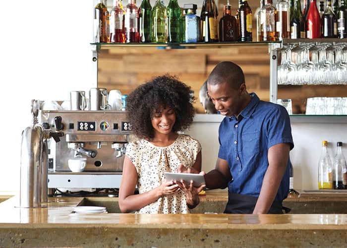 Café staff reviewing information on a tablet while standing behind their service counter