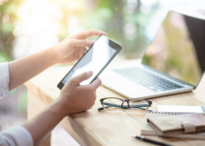 Business professional accessing information on a smartphone at a desk with a laptop nearby