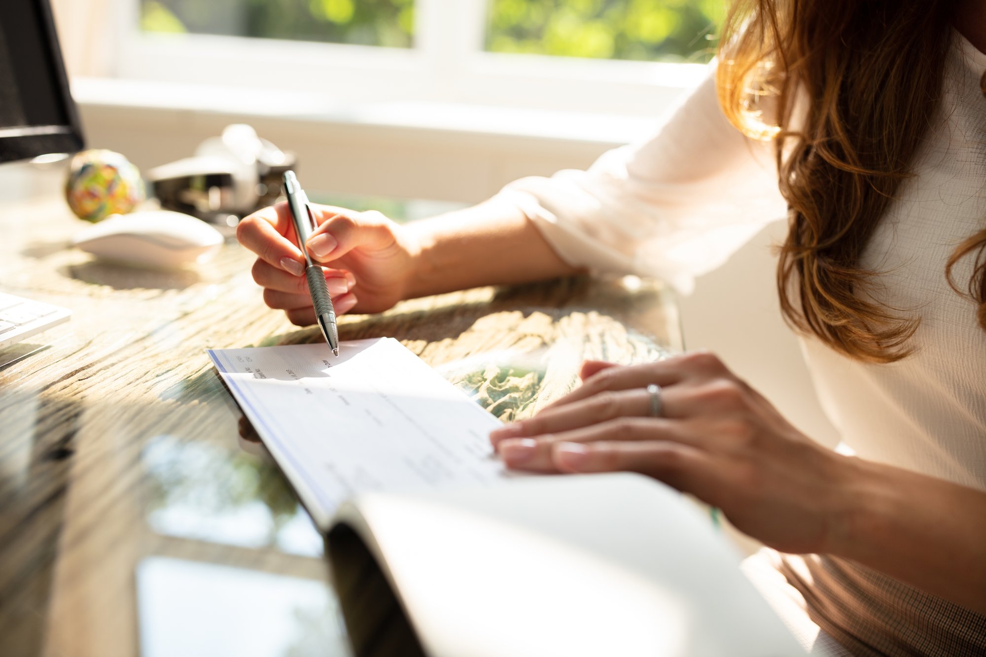 Woman writing a check while seated at her desk