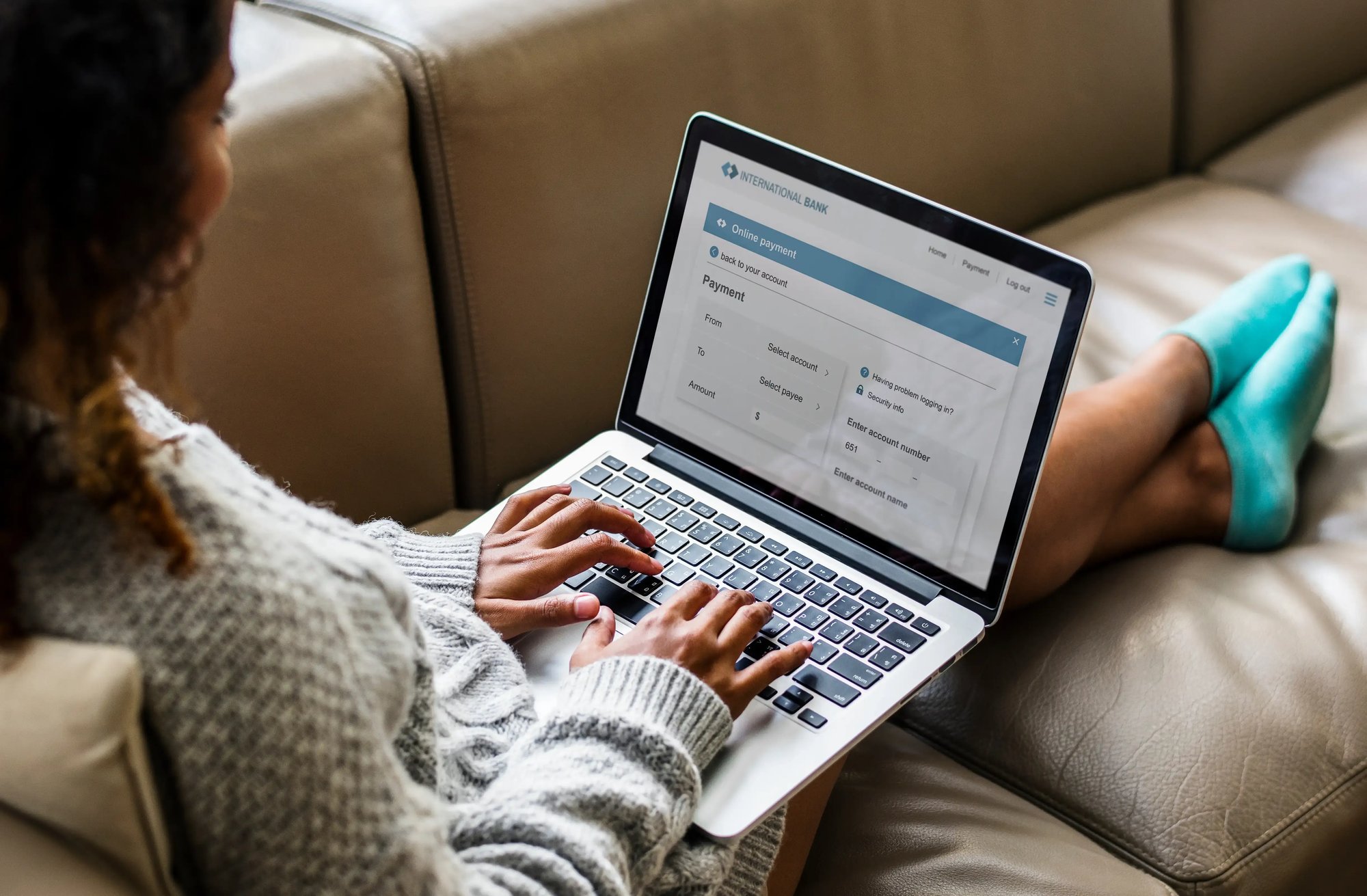 Woman lounging on a couch while using her laptop to access a secure online payment portal