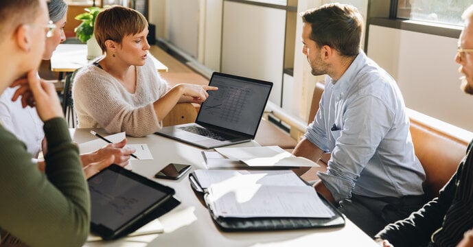 Female executive showing colleagues financial data on her laptop during a business meeting