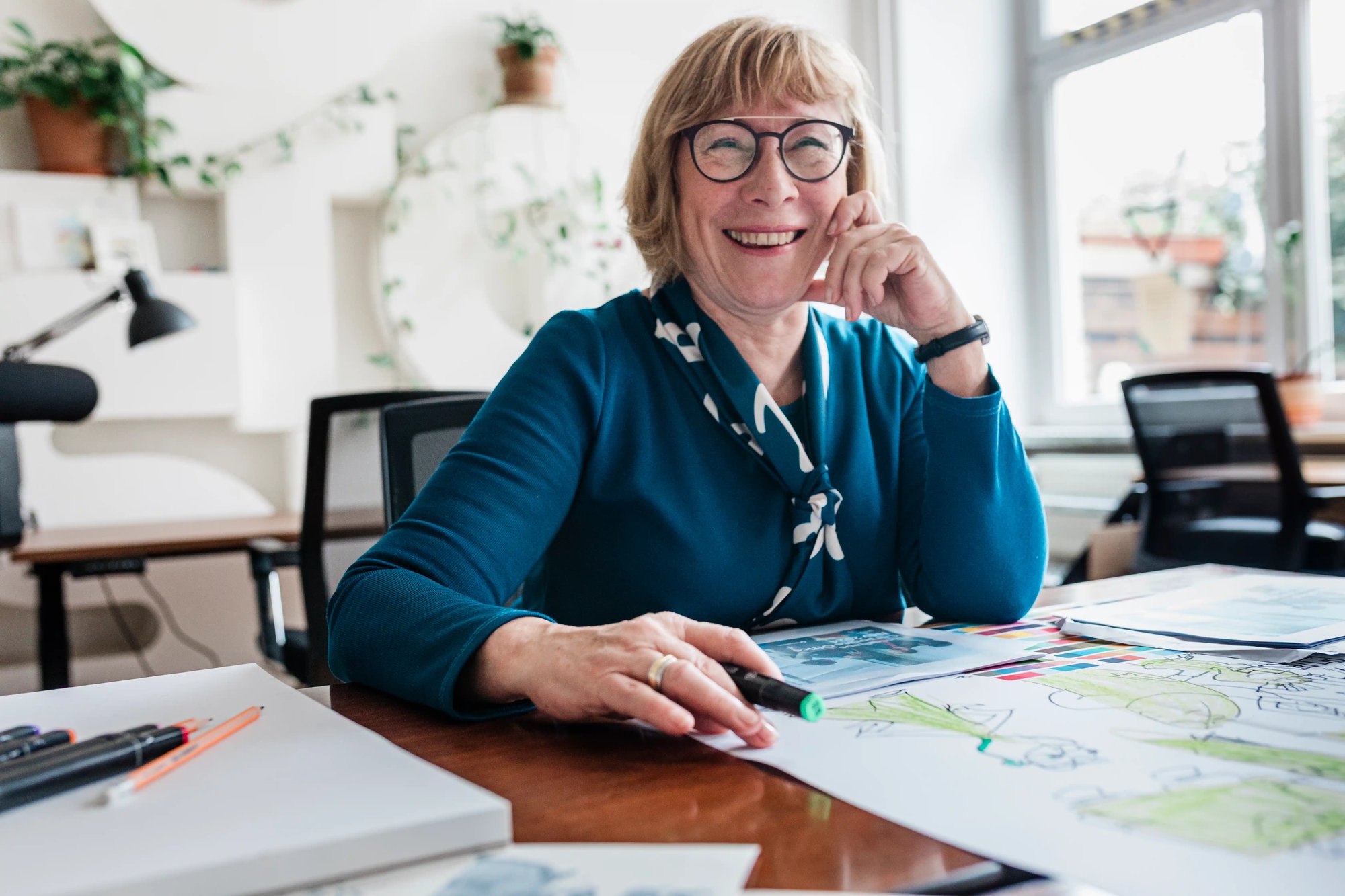 Woman smiling while reviewing design materials and working at her desk