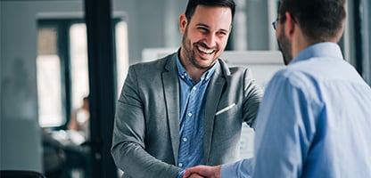 Business men smiling shaking hands.