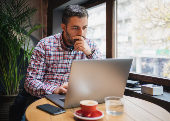 Man looking concerned at his laptop at a coffe shop.