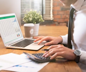man-working-on-computer-with-calculator