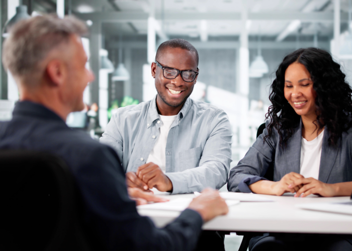 Two people talking to a banker sitting at a desk